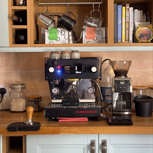 Coffee-making equipment including a coffee machine and grinder on a kitchen counter.